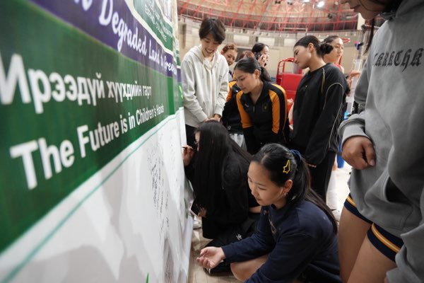 Players read the pledge — “Ирээдүй хүүхдийн гарт” — before signing.