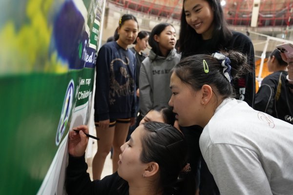 Teammates crowd in to sign together.